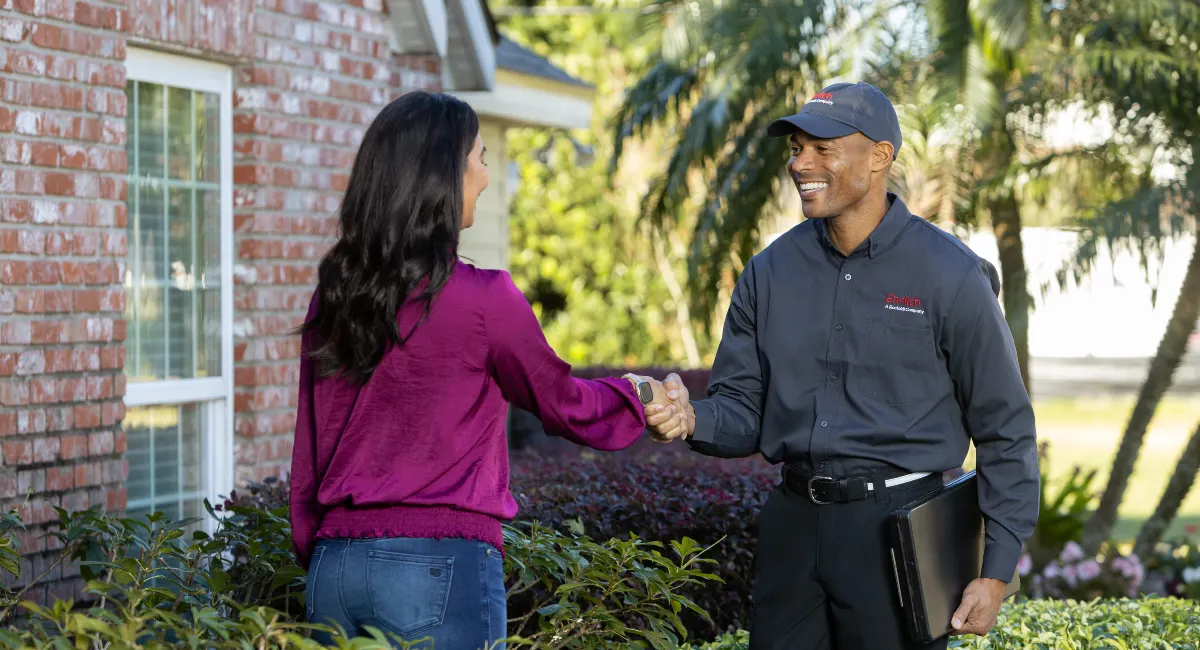 Ehrlich specialist standing in a front yard with customer