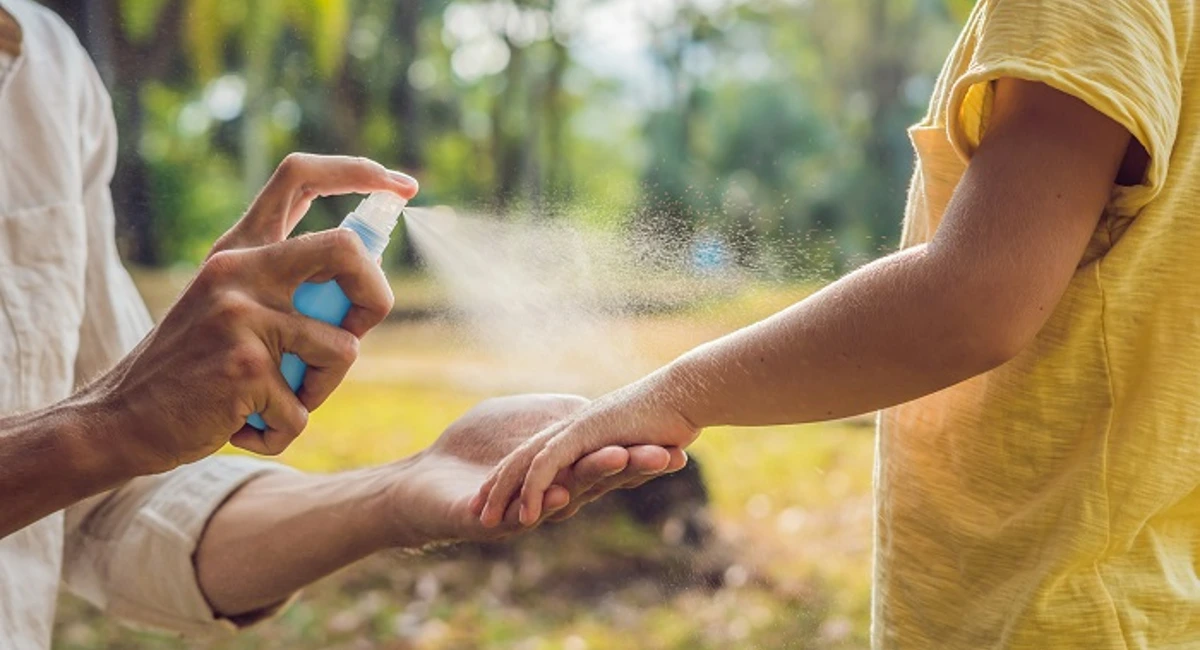 Spraying kid with mosquito repellent